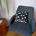 Poduszka z tkaniny welurowej w rozmiarze 34 cm x 38 cm, leży na fotelu